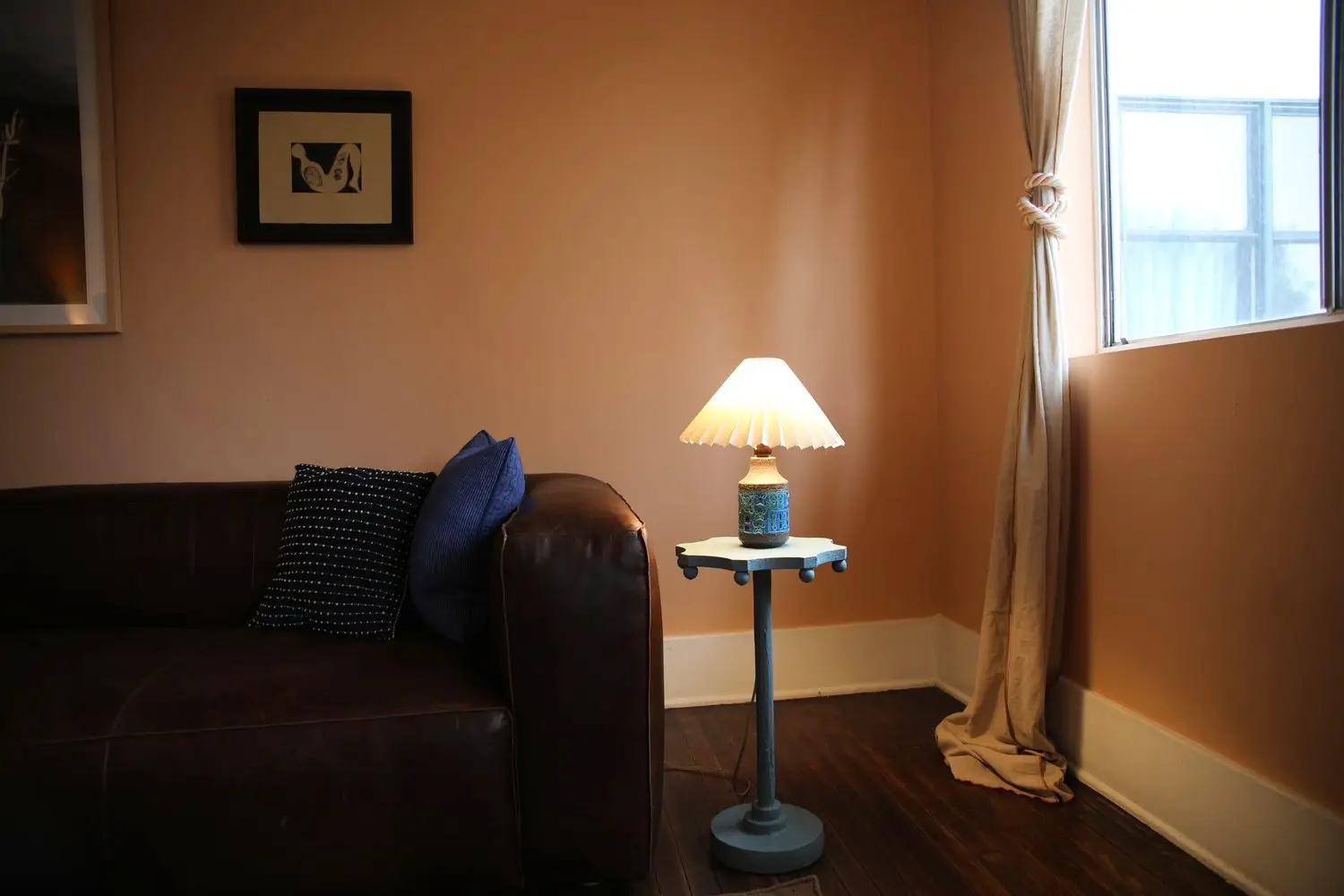 Therapy room at Inner Vision Psychotherapy with a leather sofa, glowing table lamp, and window